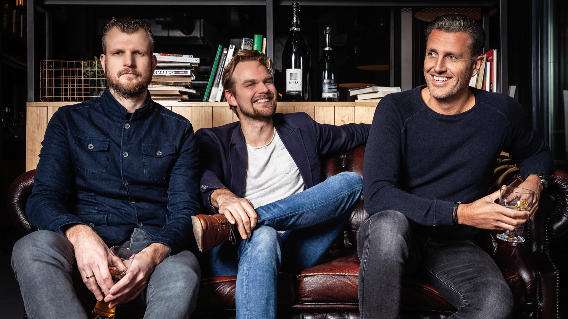 Persfoto van de drie bandleden van KOESTER op een leren bank